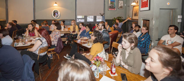 people seated around tables listening to a talk